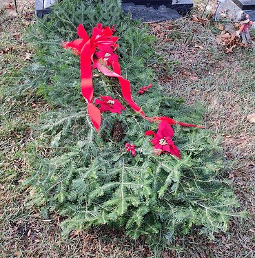 Grave blankets with pine cones, berries and a bow